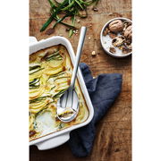 Servierlöffel NUOVA 25CM in einer Auflaufform mit Zucchini-Auflauf, von oben fotografiert.