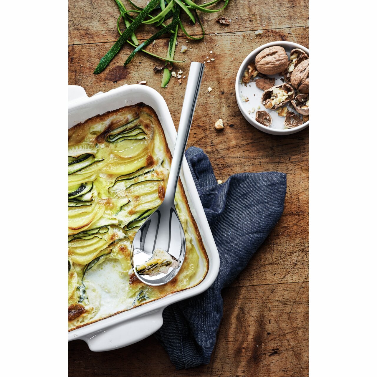 WMF Servierlöffel 25cm NUOVA Servierlöffel NUOVA 25CM in einer Auflaufform mit Zucchini-Auflauf, von oben fotografiert.