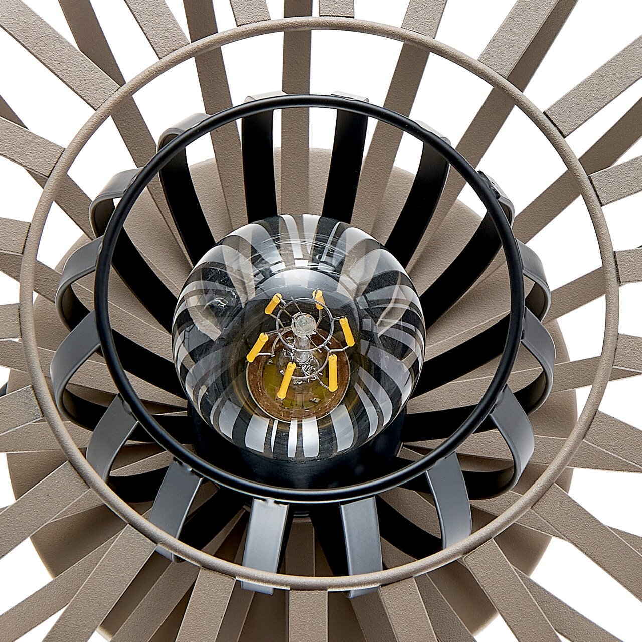 Close-up van een tafellamp van bovenaf, waarop het ontwerp met concentrische cirkels en een centrale gloeilamp te zien is.