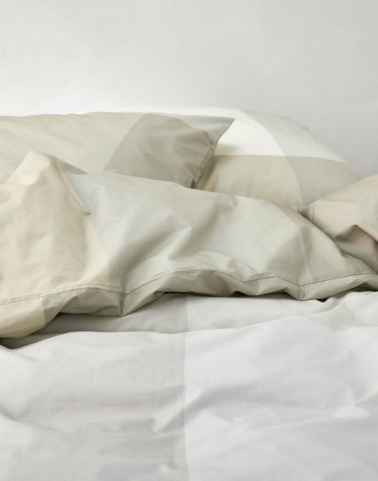 Nahaufnahme von Bettwäsche in sanften Beige- und Grautönen mit geometrischem Muster.