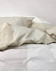 Nahaufnahme von Bettwäsche in sanften Beige- und Grautönen mit geometrischem Muster.