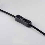 Schwarzer Schnur-Zwischenschalter (Ein/Aus) an einem textilummantelten Kabel, Nahaufnahme in leicht schräger Seitenansicht auf hellem Hintergrund