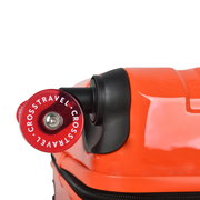 Nahaufnahme eines roten Koffer-Rads mit der Aufschrift „CROSSTRAVEL“ an einem orangefarbenen Hartschalenkoffer, Seitenansicht/Detailperspektive.