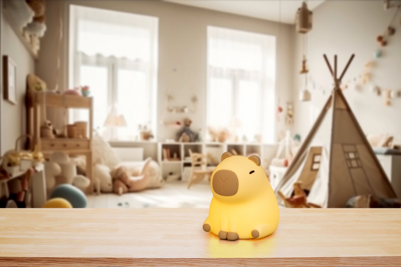 Niedliches Akku-Nachtlicht in Form eines sitzenden Tieres auf einem Tisch, mit einem gemütlichen Kinderzimmer im Hintergrund, Frontalansicht.