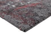 Nahaufnahme eines modernen Teppichs in Grau- und Rottönen, perspektivisch von der Seite aufgenommen.