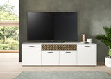 Weißes Lowboard mit geometrischem Muster in der Mitte, darauf ein großer Fernseher, umgeben von dekorativen Vasen und Pflanzen, frontale Perspektive.