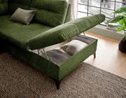 Grünes Ecksofa mit Stauraum, geöffnet, von schräg oben fotografiert, zeigt Kissen und Decke im Stauraum.