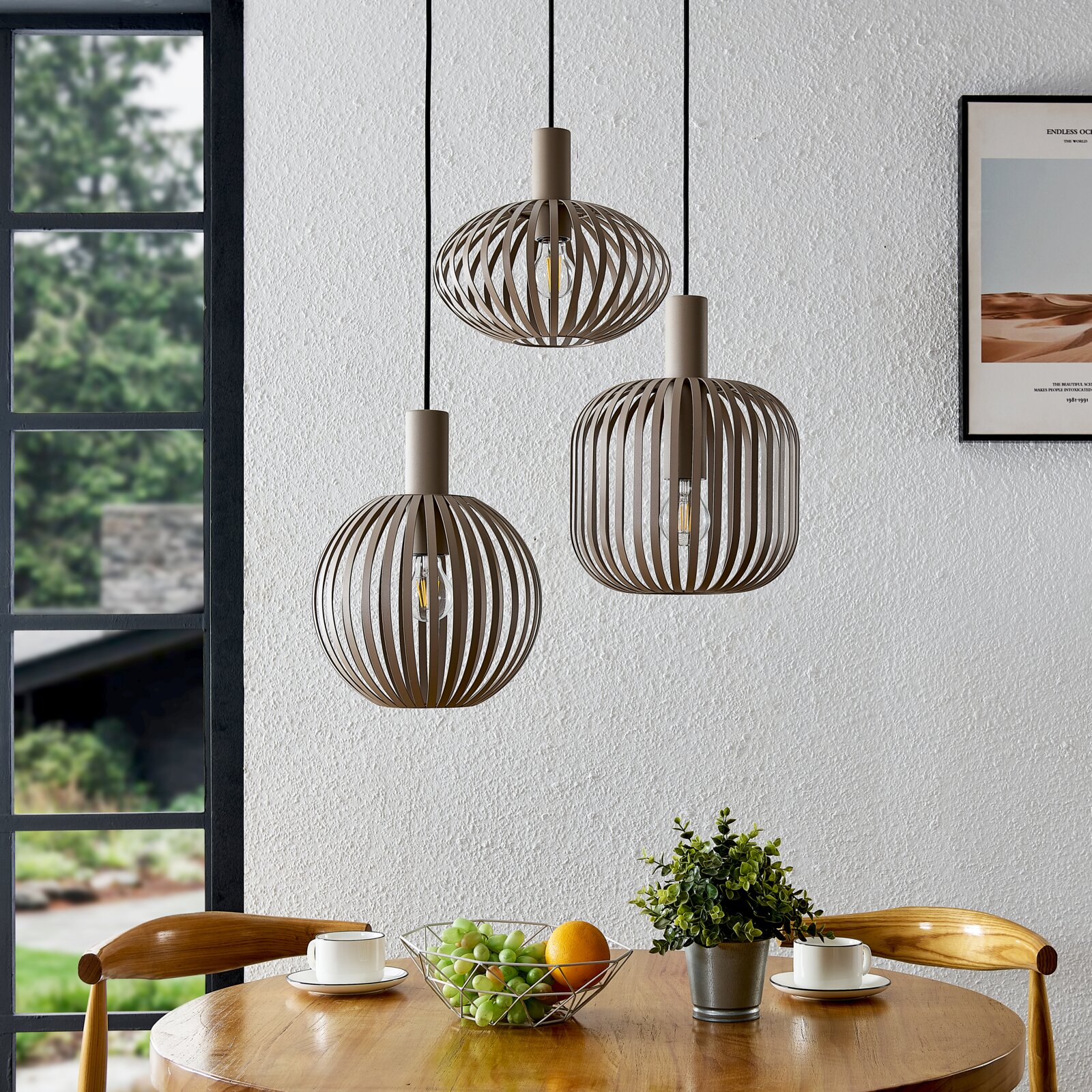 Drei moderne Pendelleuchten mit offenem, lamellenförmigem Schirm in Taupe/Beige hängen über einem Holztisch in einem Esszimmer; Perspektive: frontale Innenraumaufnahme auf Augenhöhe.