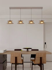 Vooraanzicht van een moderne viervoudige hanglamp met goudkleurige schotelkappen en warm licht boven een eettafel