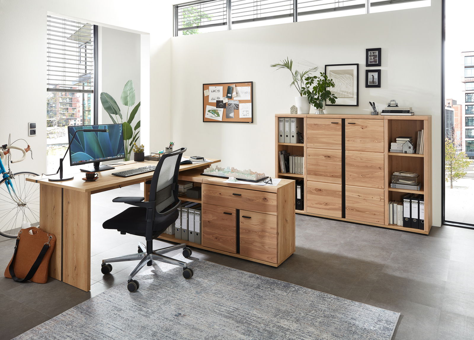 Büroeinrichtung mit Schreibtisch, Rollcontainer und Aktenschrank aus Holz in einem modernen, hellen Raum. Perspektive von vorne links.