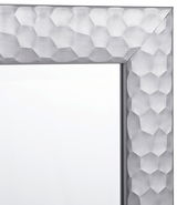 Nahaufnahme eines Spiegels mit einem silbernen, geometrisch gemusterten Rahmen, Perspektive von der Ecke.