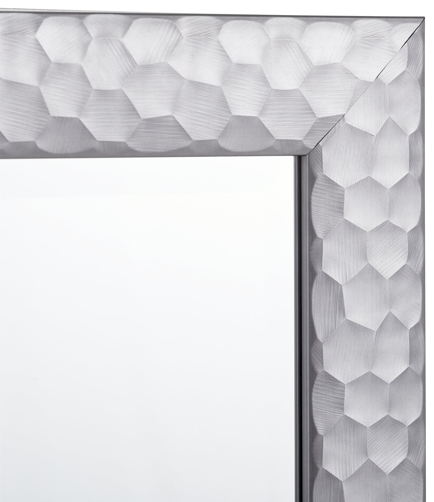 Nahaufnahme eines Spiegels mit einem silbernen, geometrisch gemusterten Rahmen, Perspektive von der Ecke.