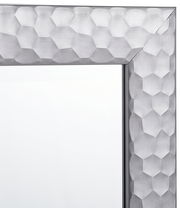 Nahaufnahme eines Spiegels mit einem silbernen, geometrisch gemusterten Rahmen, Perspektive von der Ecke.