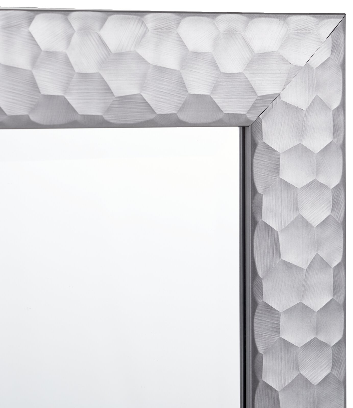 Nahaufnahme eines Spiegels mit einem silbernen, geometrisch gemusterten Rahmen, Perspektive von der Ecke.