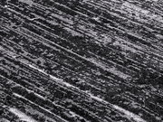 Nahaufnahme eines Designer Teppichs mit diagonalen, strukturierten Linien in Grautönen, aus der Vogelperspektive aufgenommen.