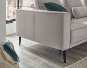 Rundecke in hellem Stoff mit schwarzen Beinen, seitliche Perspektive, dekoriert mit einem grünen Kissen.