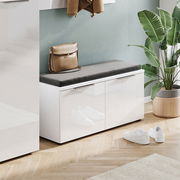 Moderne Garderobenbank mit weißem Hochglanz-Finish und grauem Sitzkissen, seitliche Perspektive, dekoriert mit einer Tasche und umgeben von Pflanzen.