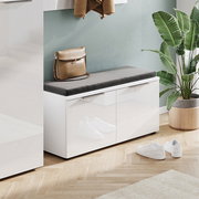 Moderne Garderobenbank mit weißem Hochglanz-Finish und grauem Sitzkissen, seitliche Perspektive, dekoriert mit einer Tasche und umgeben von Pflanzen.