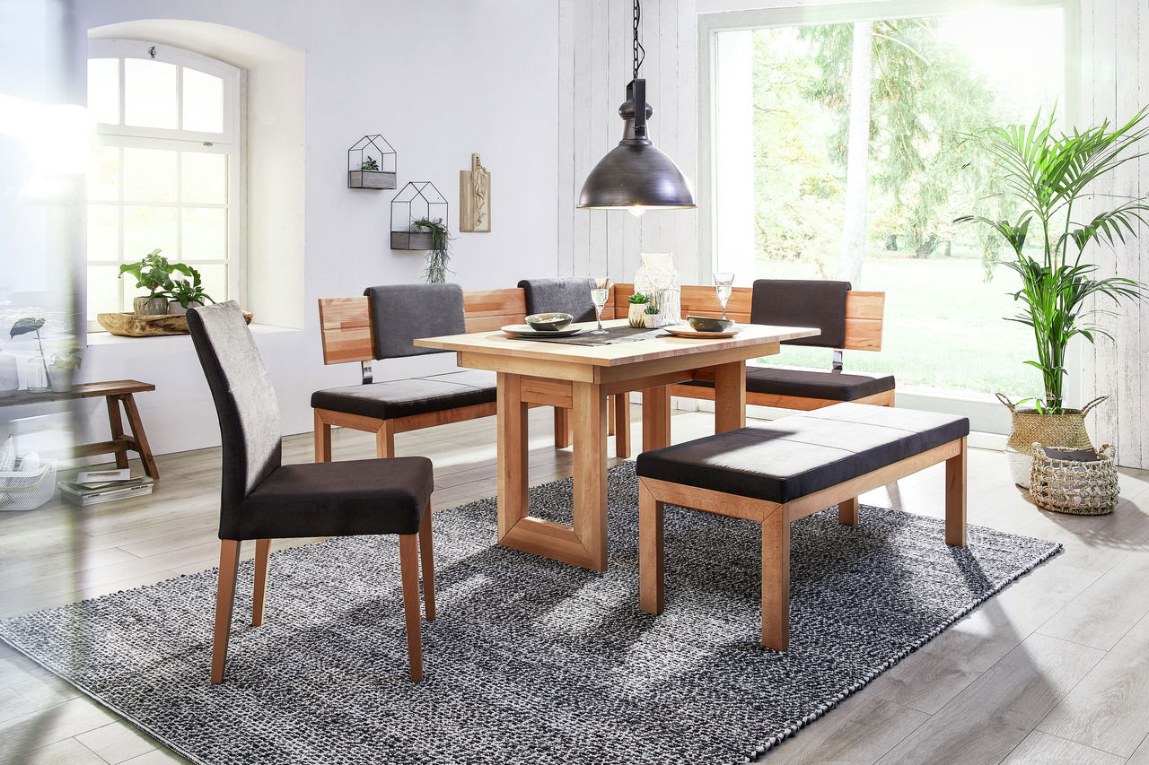Moderner Esstisch aus Holz mit passender Sitzbank und Stühlen in einem hellen, gemütlichen Esszimmer, seitliche Perspektive.