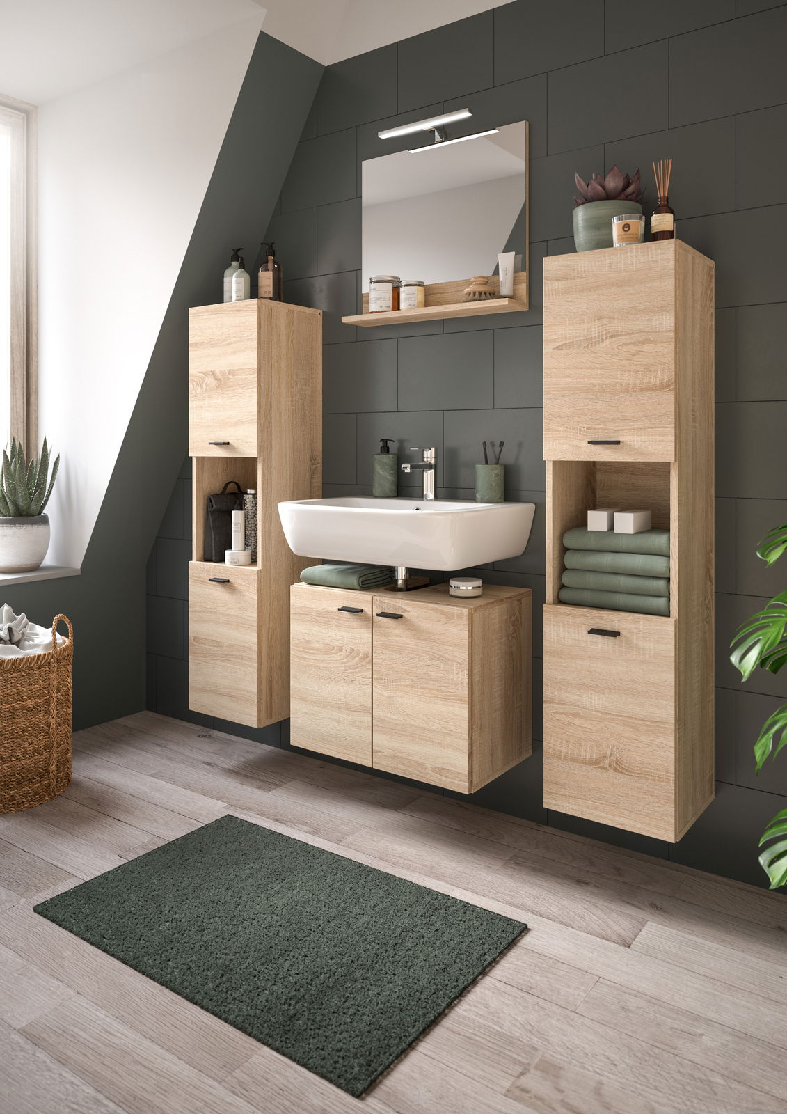 Moderne Badkombination mit Holzoptik, bestehend aus einem Waschbecken mit Unterschrank, zwei hohen Schränken und einem Spiegel, aus der Perspektive eines hellen Badezimmers mit Dachschräge.