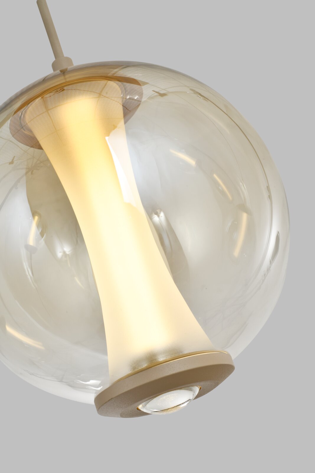 Close-up vanuit onderaanzicht van een moderne hanglamp met transparante glazen bol en warm verlichte, goudkleurige binnenkap