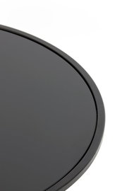 Nahaufnahme eines runden, schwarzen Couchtischs mit glatter Oberfläche, von oben betrachtet.