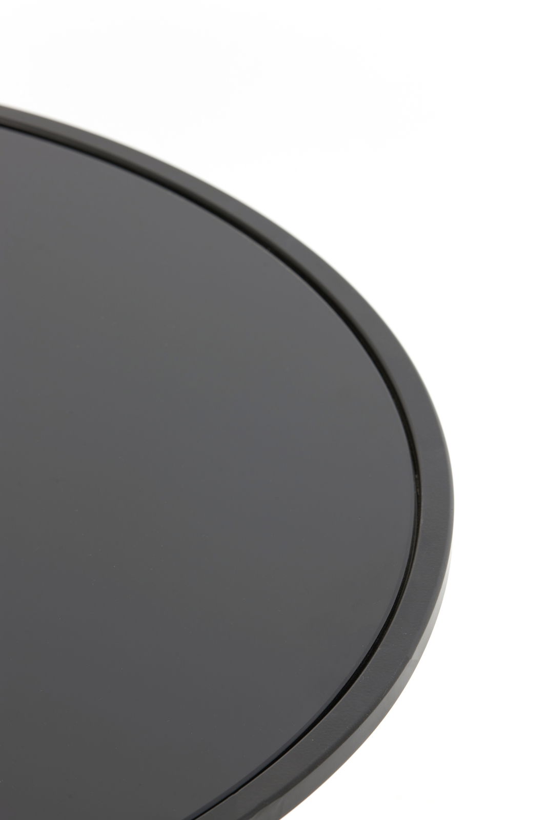 Nahaufnahme eines runden, schwarzen Couchtischs mit glatter Oberfläche, von oben betrachtet.