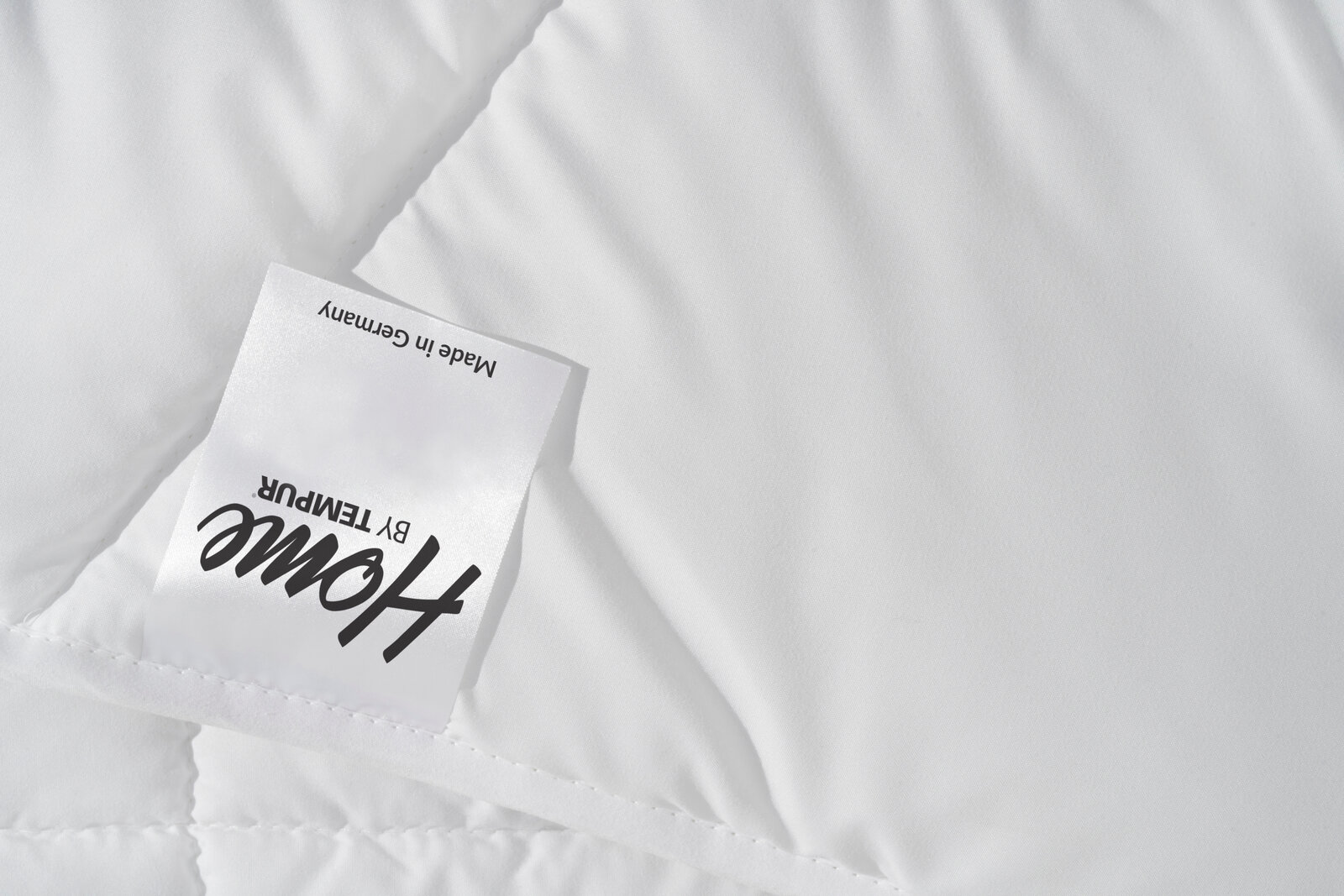 Nahaufnahme einer weißen, gesteppten Decke mit einem Etikett, das 'Made in Germany' zeigt.