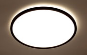 Runde LED-Deckenleuchte mit schwarzem Rahmen, von unten betrachtet, leuchtet hell mit einem sanften Lichtschein an der Decke.