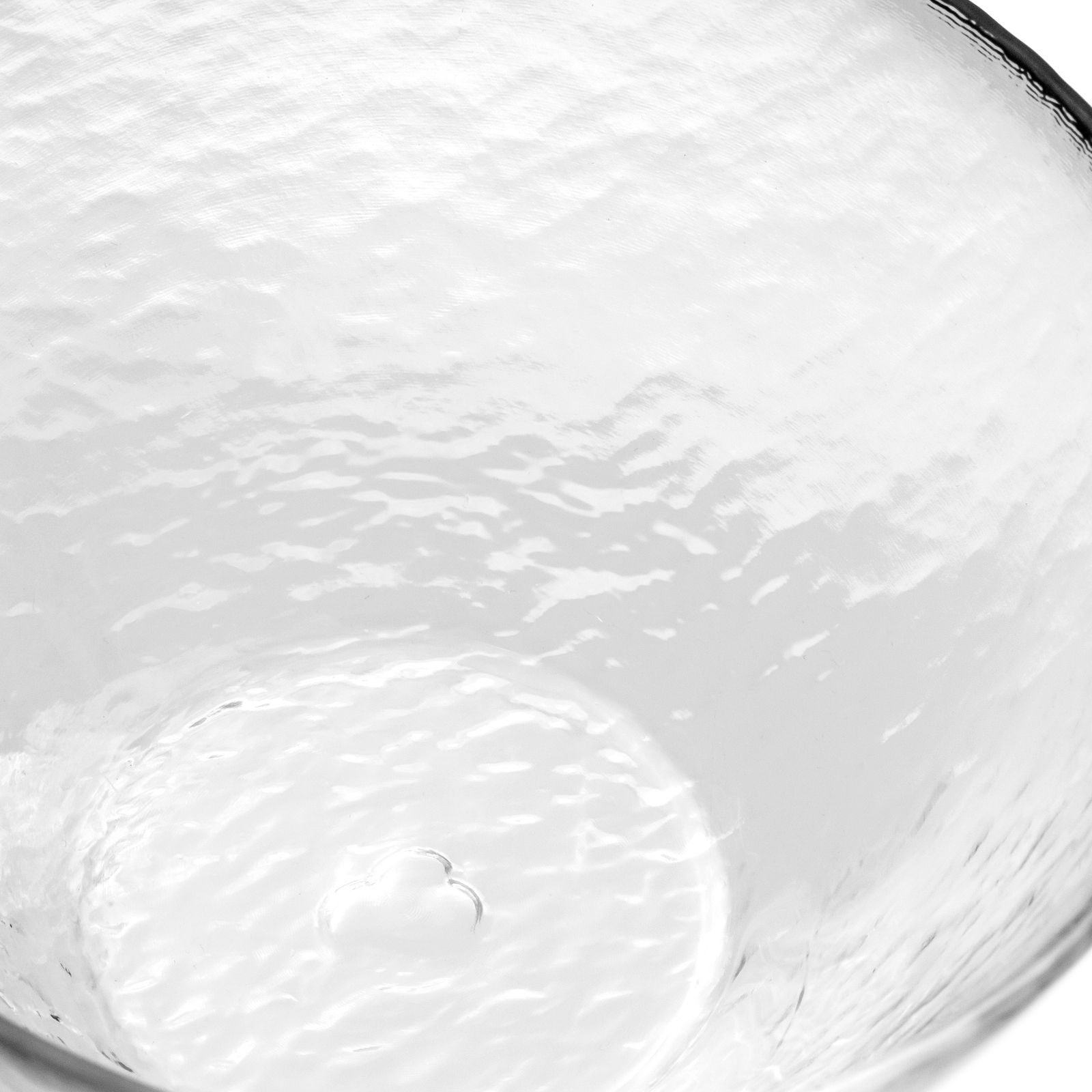 Nahaufnahme einer transparenten, strukturierten Glasschale mit wellenförmiger Oberfläche, von oben betrachtet.