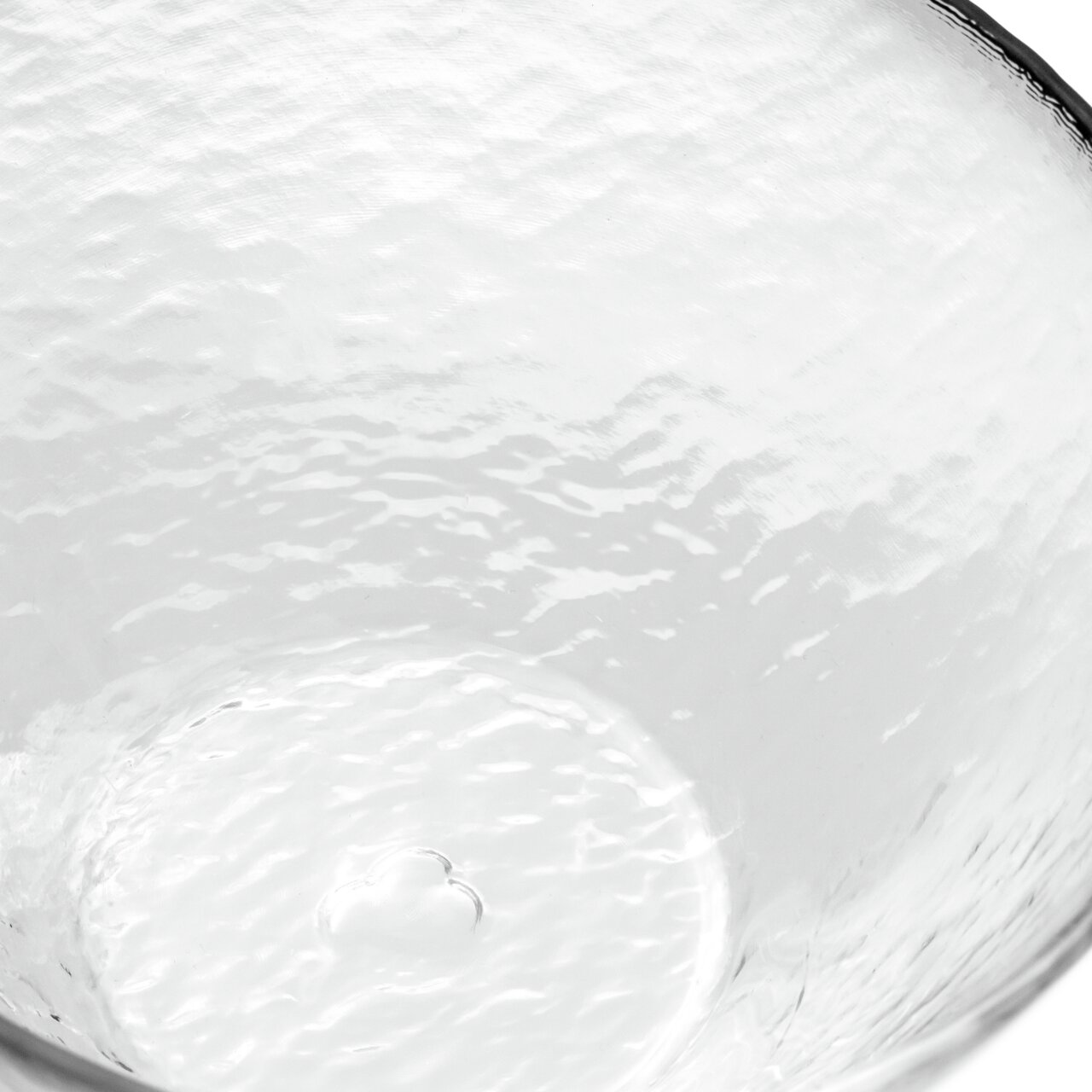 Nahaufnahme einer transparenten, strukturierten Glasschale mit wellenförmiger Oberfläche, von oben betrachtet.