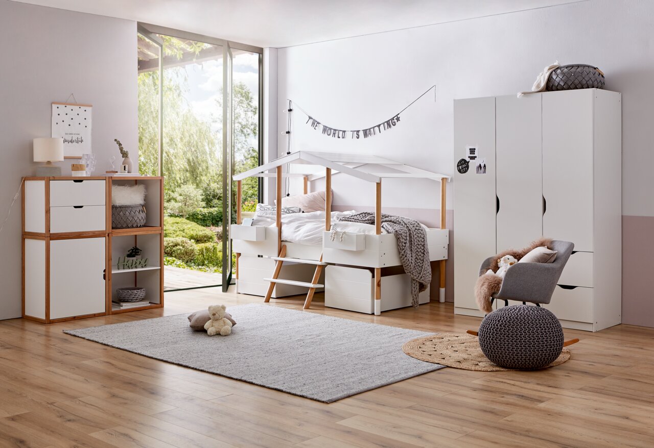 Kinderzimmer mit Hausbett, Kleiderschrank und Bücherregal in moderner, heller Einrichtung. Perspektive von der Seite.