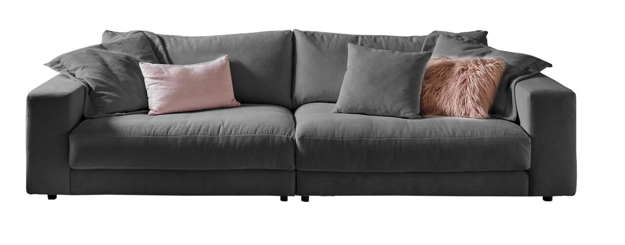 Graues Big-Sofa mit mehreren Kissen, darunter ein rosa Kissen und ein flauschiges Kissen, frontal fotografiert.