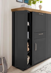 Schwarzes Highboard mit Karussellfunktion, seitliche Perspektive, mit Holzplatte und modernen Griffen, dekoriert mit Pflanzen und Büchern.
