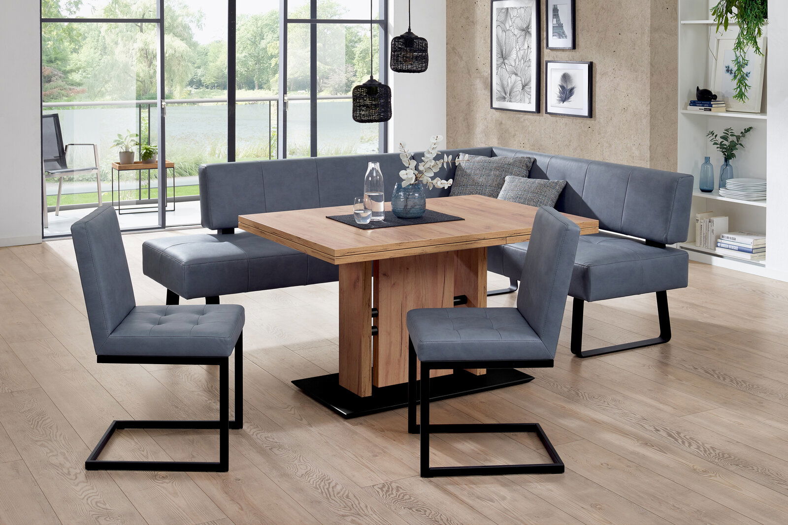 Moderano Freischwinger-Stuhl LUPO II Moderne Essgruppe mit Eckbank und Freischwinger-Stühlen in grauem Stoff, kombiniert mit einem Holztisch. Die Perspektive zeigt die Essgruppe in einem hellen Raum mit großen Fenstern im Hintergrund.