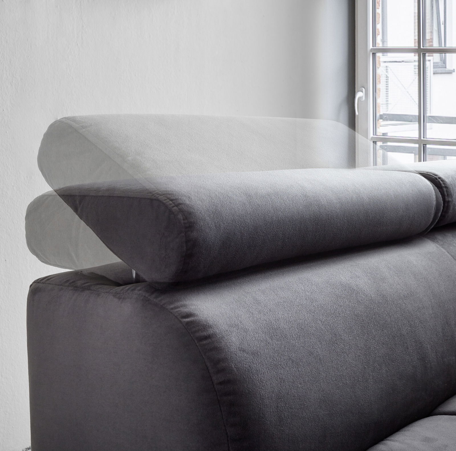 Verstellbare Kopfstütze einer grauen Polsterrundecke, seitliche Perspektive mit Fenster im Hintergrund.