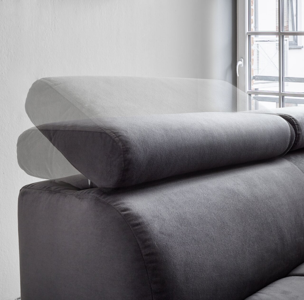 Verstellbare Kopfstütze einer grauen Polsterrundecke, seitliche Perspektive mit Fenster im Hintergrund.