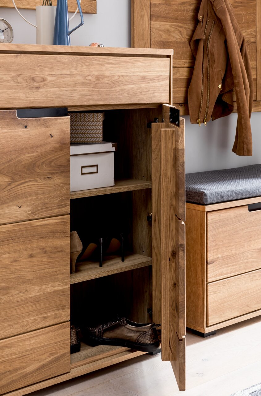 Offener Schuhschrank aus Holz mit mehreren Fächern, gefüllt mit Schuhen und einer Aufbewahrungsbox, aus seitlicher Perspektive fotografiert.