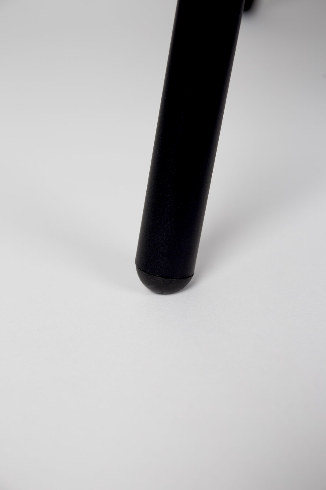 Nahaufnahme eines schwarzen Stuhlbeins auf weißem Hintergrund, Perspektive von unten.