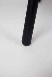 Nahaufnahme eines schwarzen Stuhlbeins auf weißem Hintergrund, Perspektive von unten.