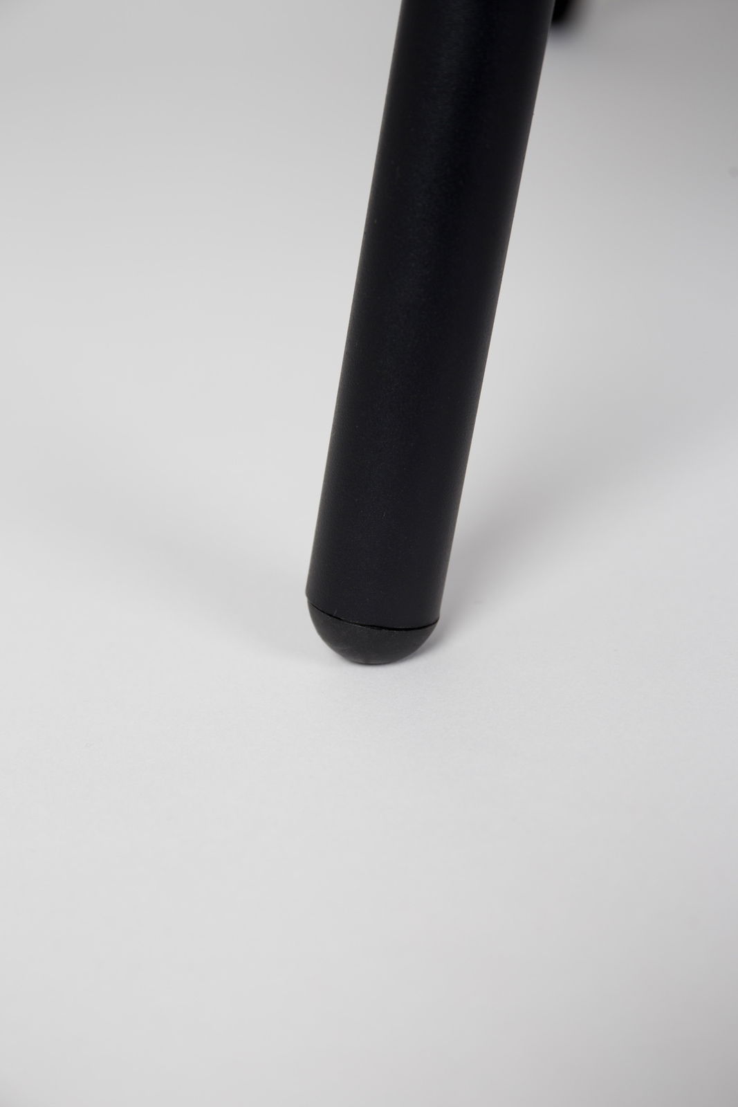 Nahaufnahme eines schwarzen Stuhlbeins auf weißem Hintergrund, Perspektive von unten.