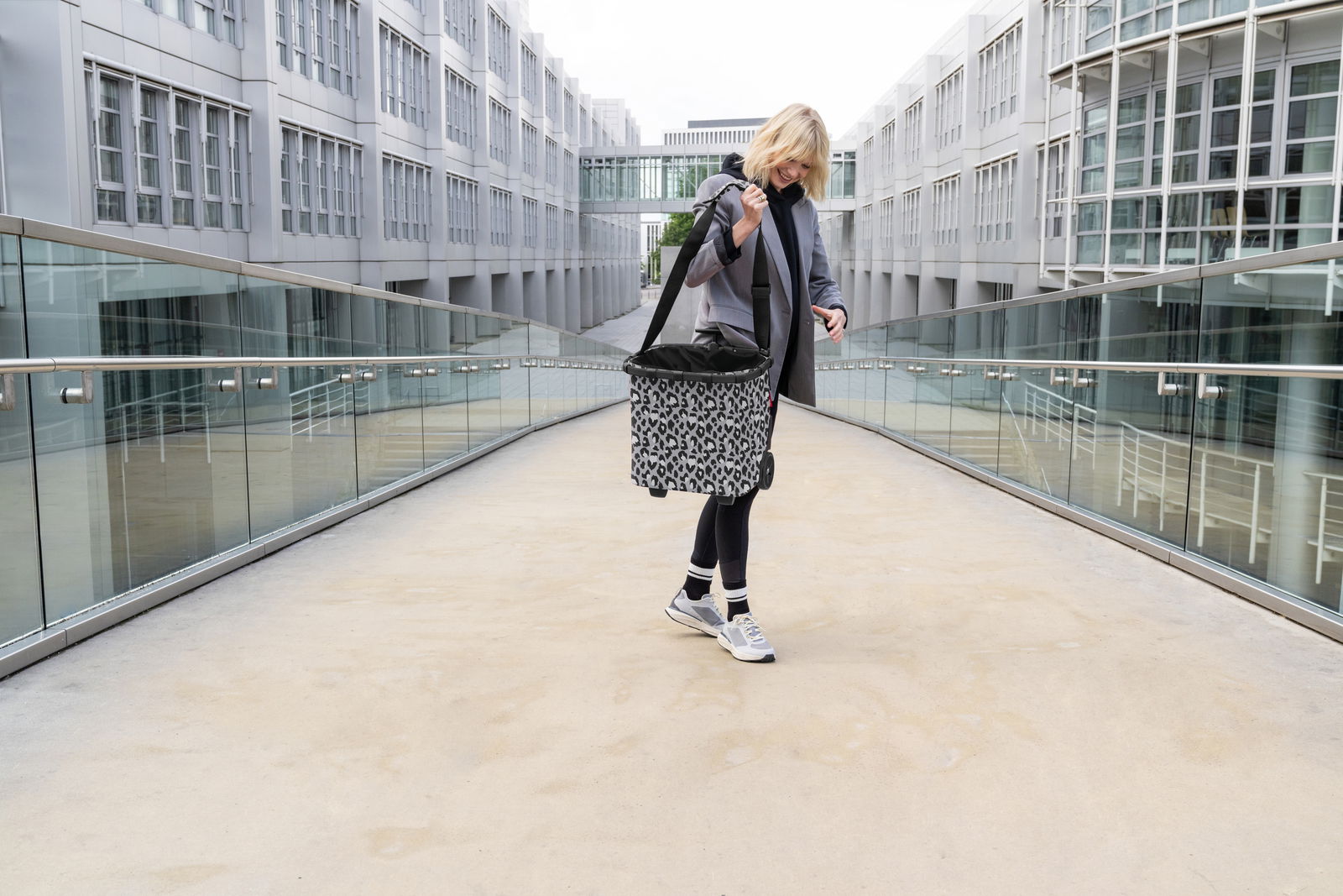 Frau mit einem Carrycruiser im Leo-Design auf einer modernen Brücke, seitliche Perspektive