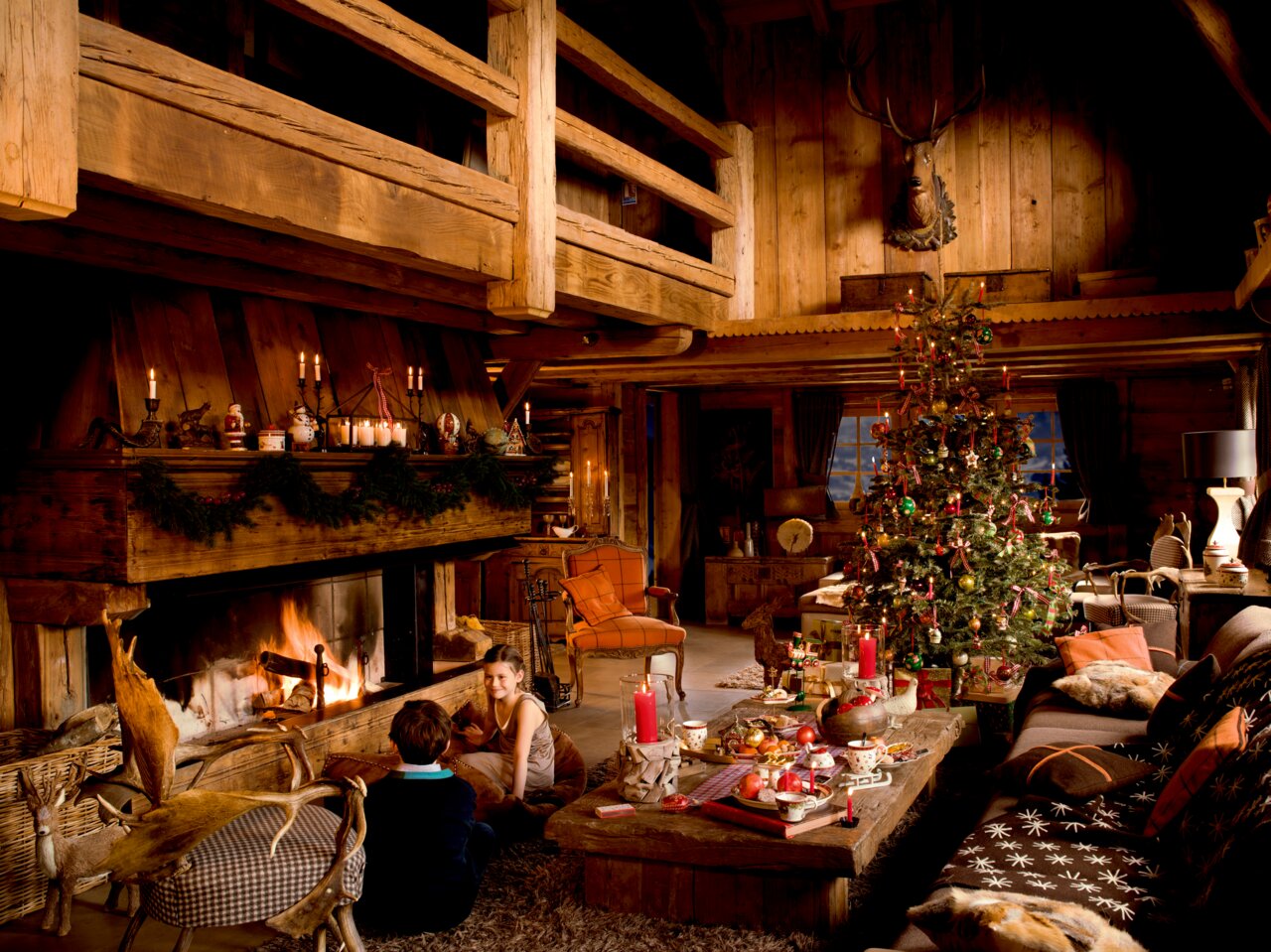 Gemütliche Weihnachtsstimmung in einer rustikalen Holzhütte mit Kaminfeuer, geschmücktem Weihnachtsbaum und festlich gedecktem Tisch mit Bechern. Perspektive: Innenansicht des Wohnzimmers.