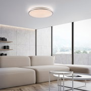 Runde, flache LED-Deckenleuchte in Weiß mit funkelndem Sternenhimmel-Effekt, an der Decke eines modernen Wohnzimmers montiert, Perspektive von unten leicht schräg nach oben.