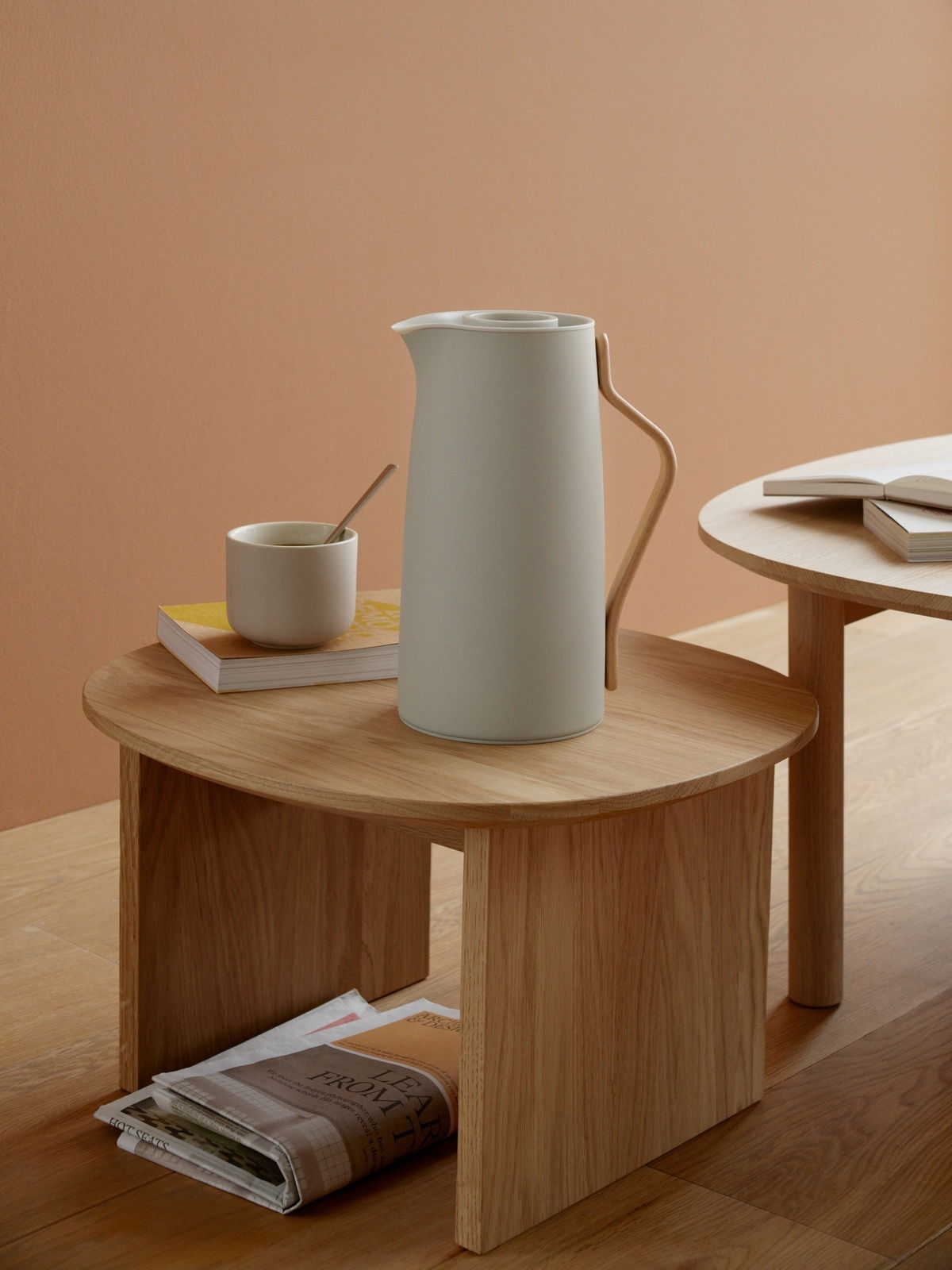 Stelton Isolierkanne EMMA Elegante Emma Isolierkanne in modernem Design, seitliche Perspektive auf einem Holztisch mit Tasse und Büchern.