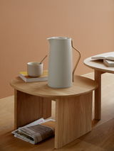Elegante Emma Isolierkanne in modernem Design, seitliche Perspektive auf einem Holztisch mit Tasse und Büchern.