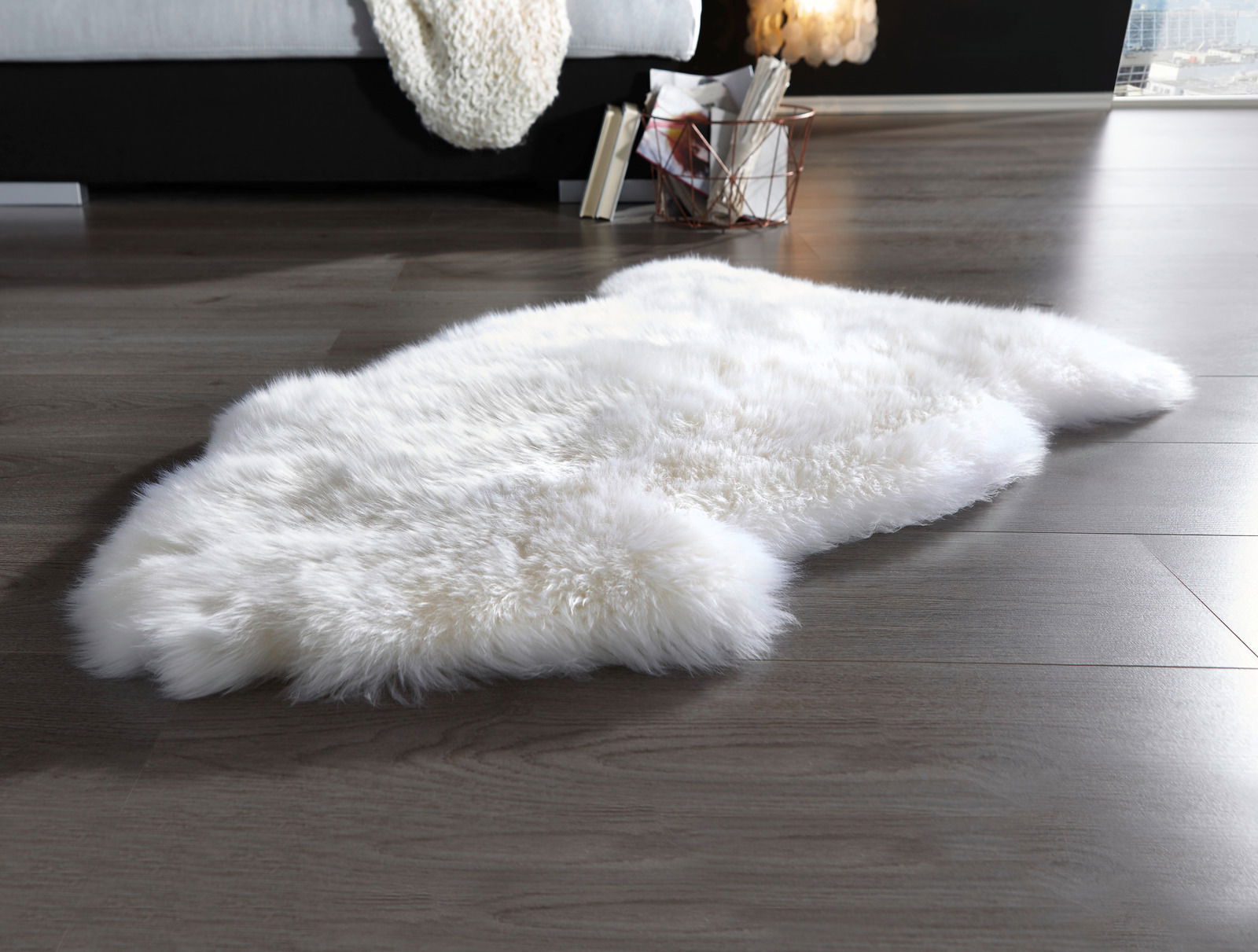 Schaffell in wollweiß auf einem Holzboden, seitliche Perspektive