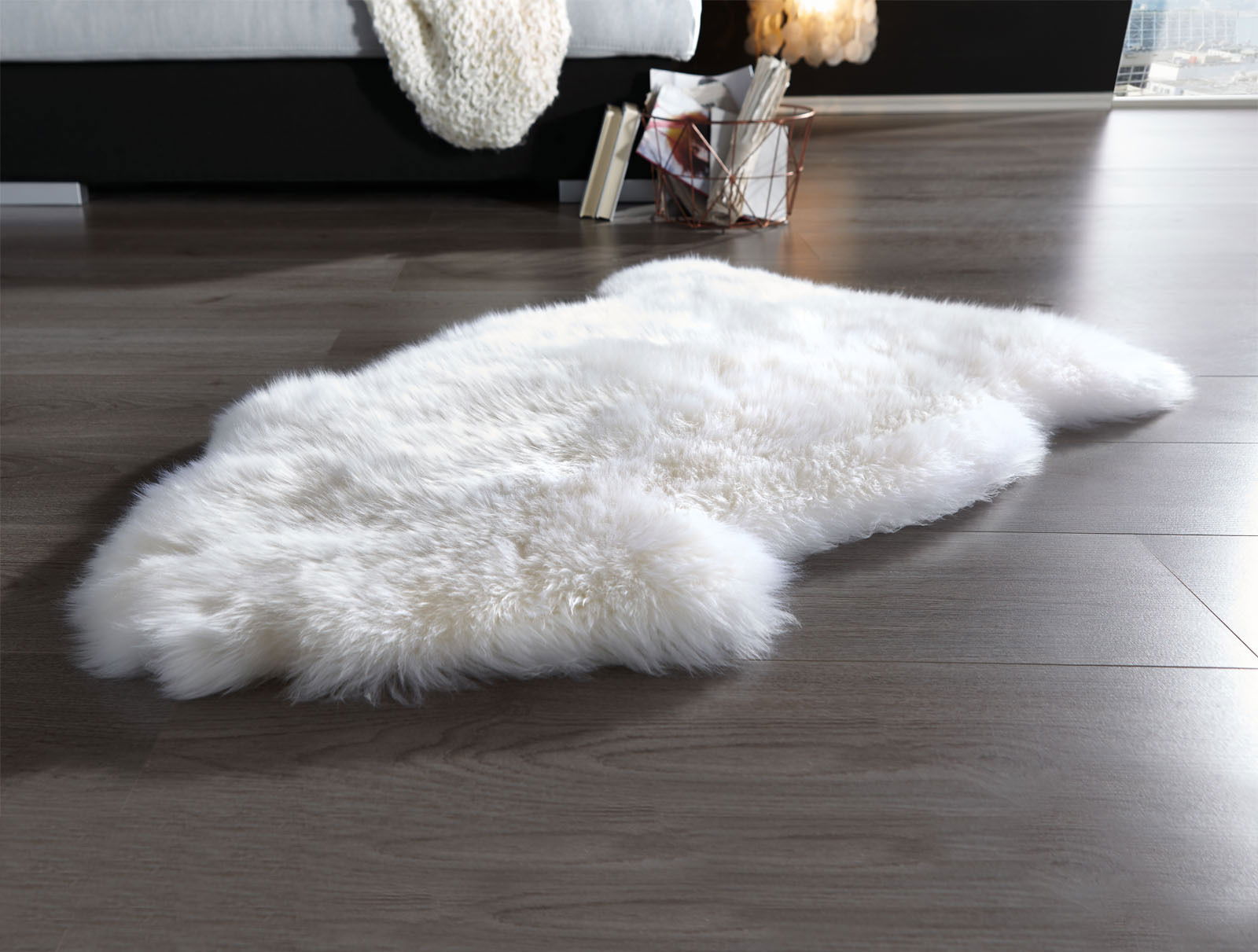 Schaffell in wollweiß auf einem Holzboden, seitliche Perspektive