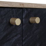 Nahaufnahme von zwei goldenen Knöpfen auf einer schwarzen, strukturierten Oberfläche eines TV-Lowboards, seitliche Perspektive