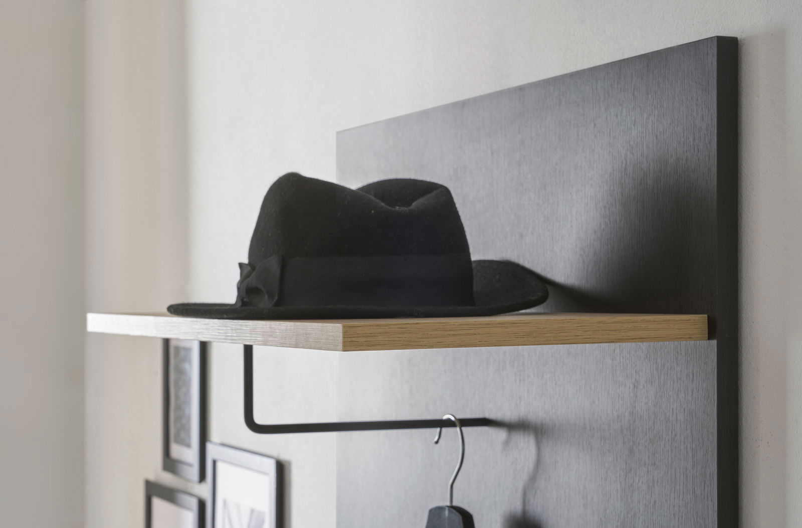 Garderobenpaneel mit schwarzem Hut auf einem Holzregal, seitliche Perspektive